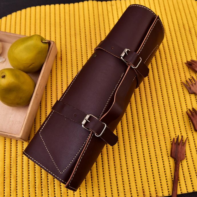 Hand-stitched leather roll storing 5-piece Damascus chef knife set with Texas flag handles and a honing rod.