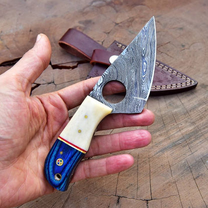 Damascus skinner knife held in hand to show compact size and finger-ring control.