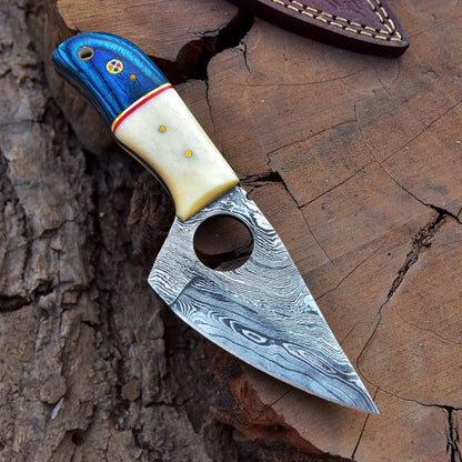 Hunting knife placed on tree stump showing detailed blade pattern and handle texture.